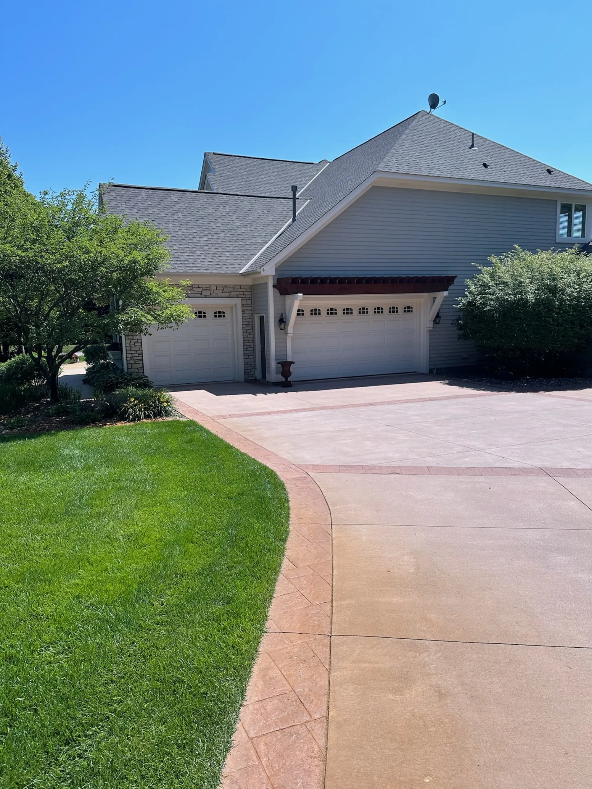 Freshly washed stained-concrete driveway under blue sky — pressure washing results Twin Cities