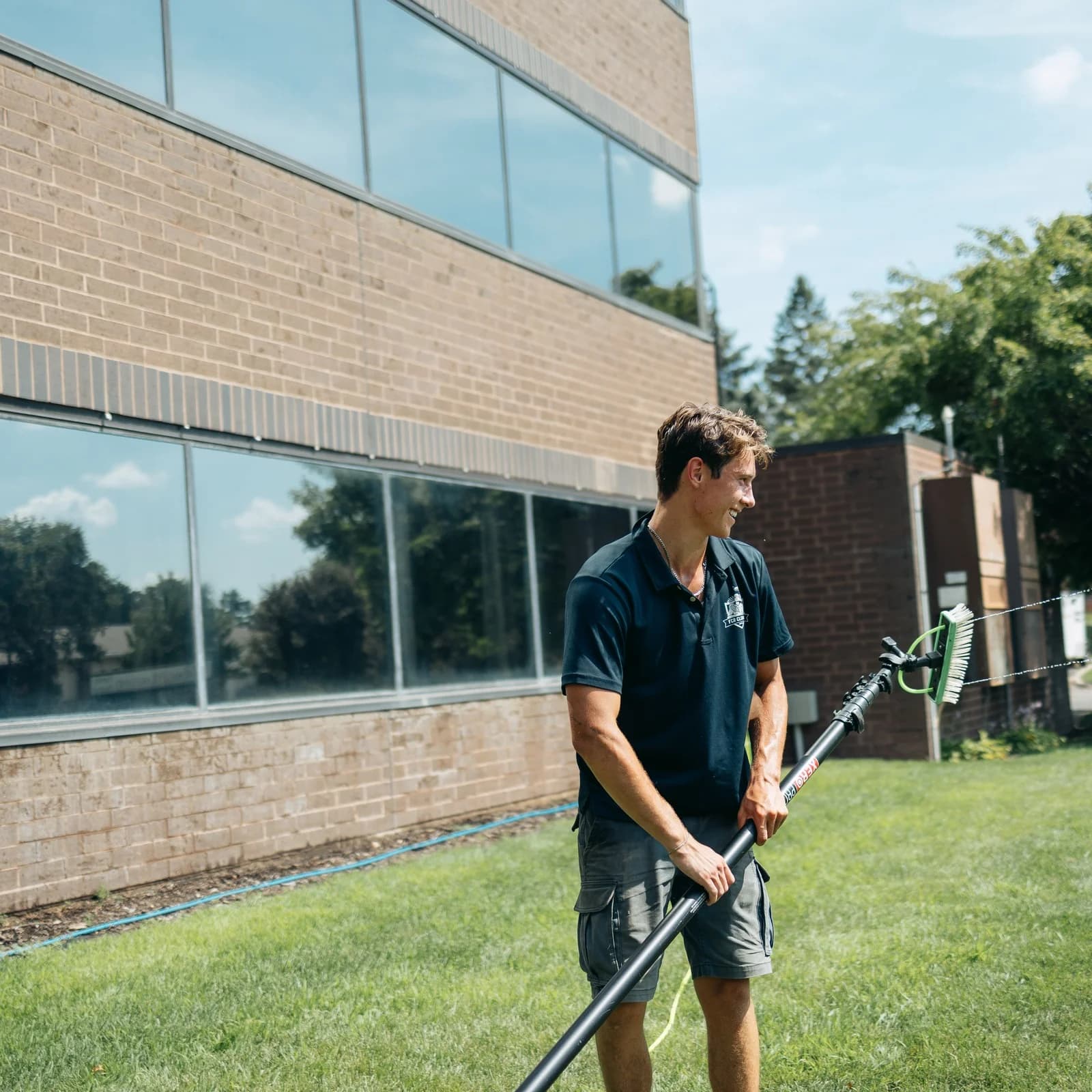 FCR technician using a water-fed pole on a multi-story office building — commercial window cleaning