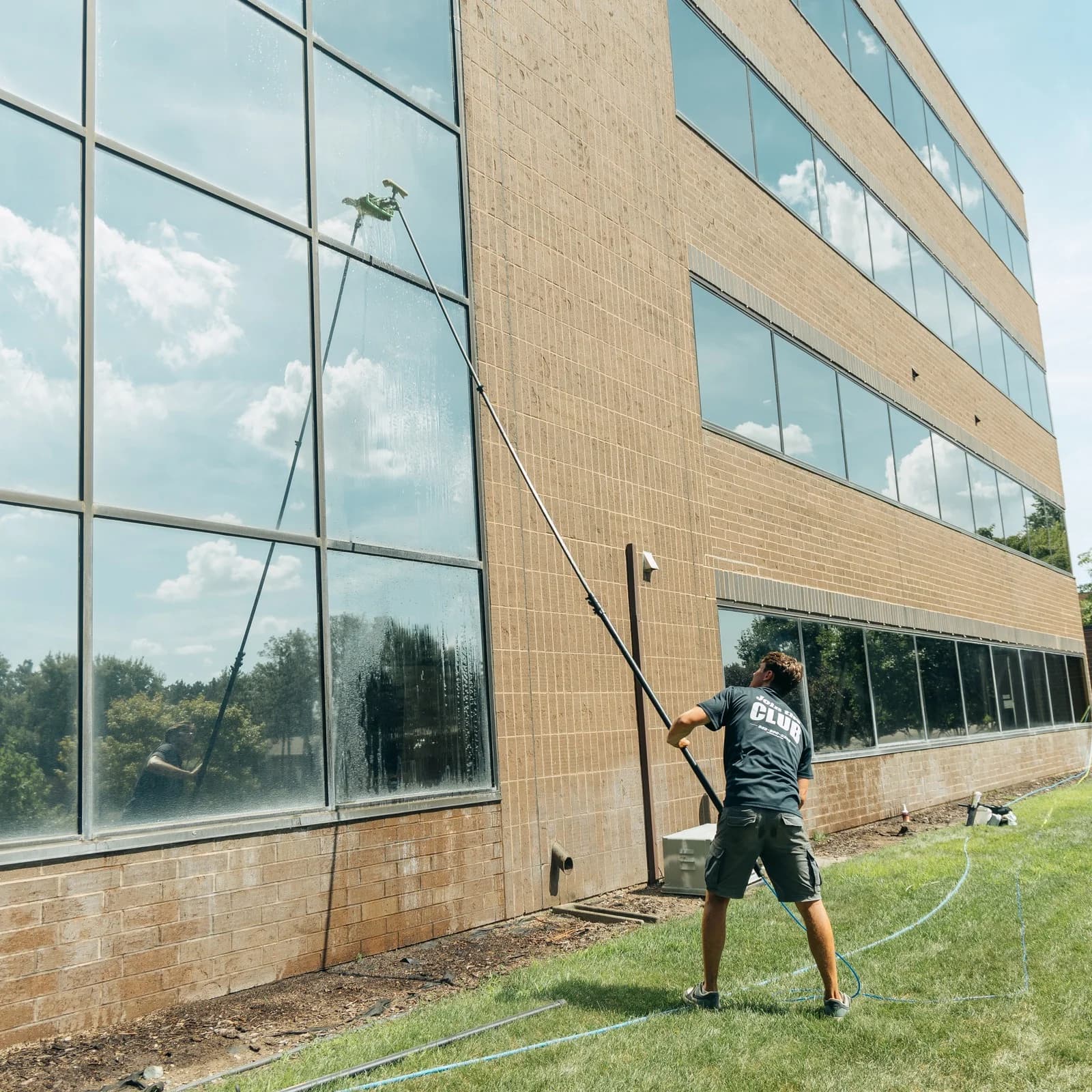 Wide shot of a technician cleaning a full office building facade top to bottom