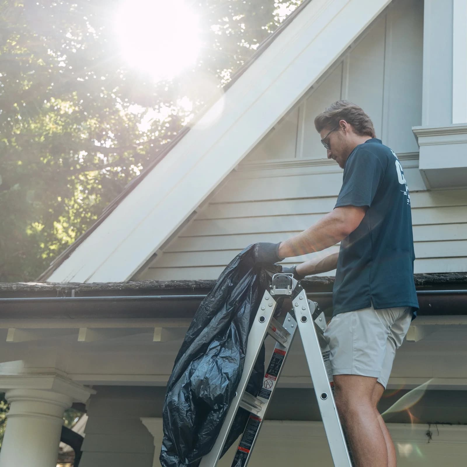 FCR technician clearing gutter debris from a ladder at a residential home
