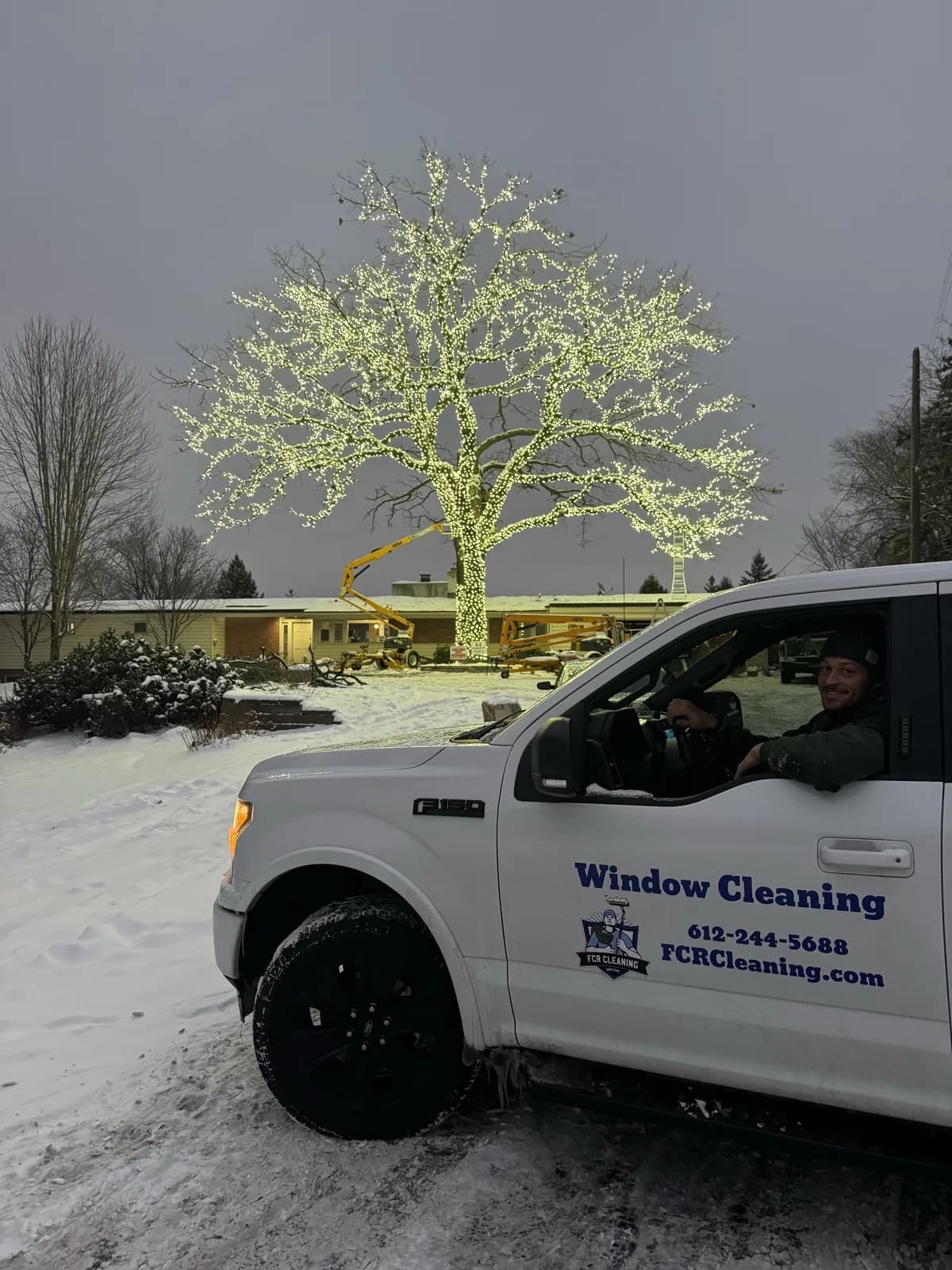 Fritz in the FCR truck as the Bloomington Lighted Oak lights up for the first time — mini lights wrapped across the front-facing side, install near completion