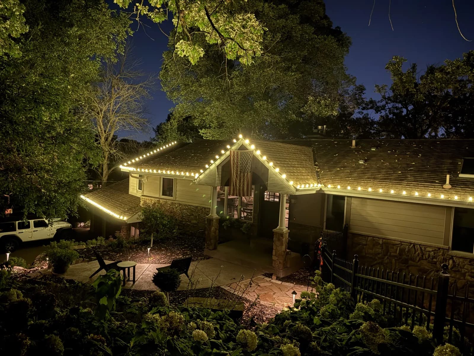 Classic roofline design — warm white C9 bulbs across the full roofline of a stone rambler