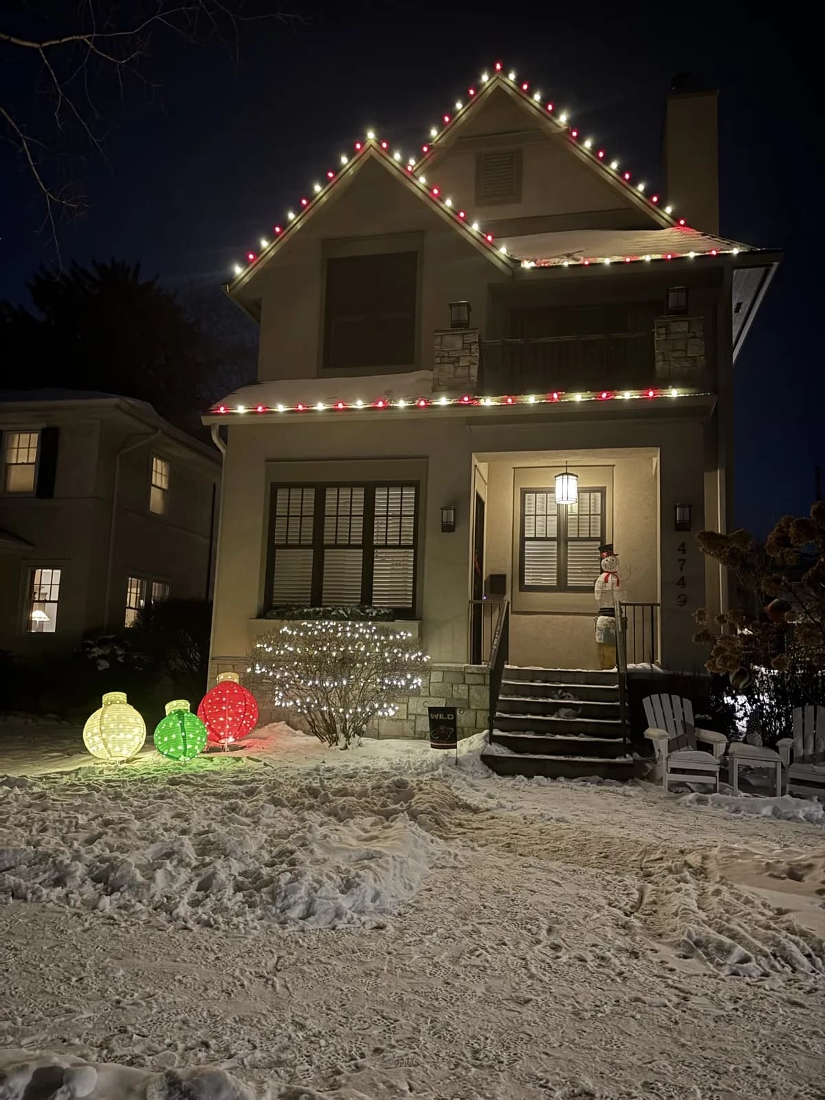 Red and white C9 bulb installation along every roofline and gable of a stucco two-story home