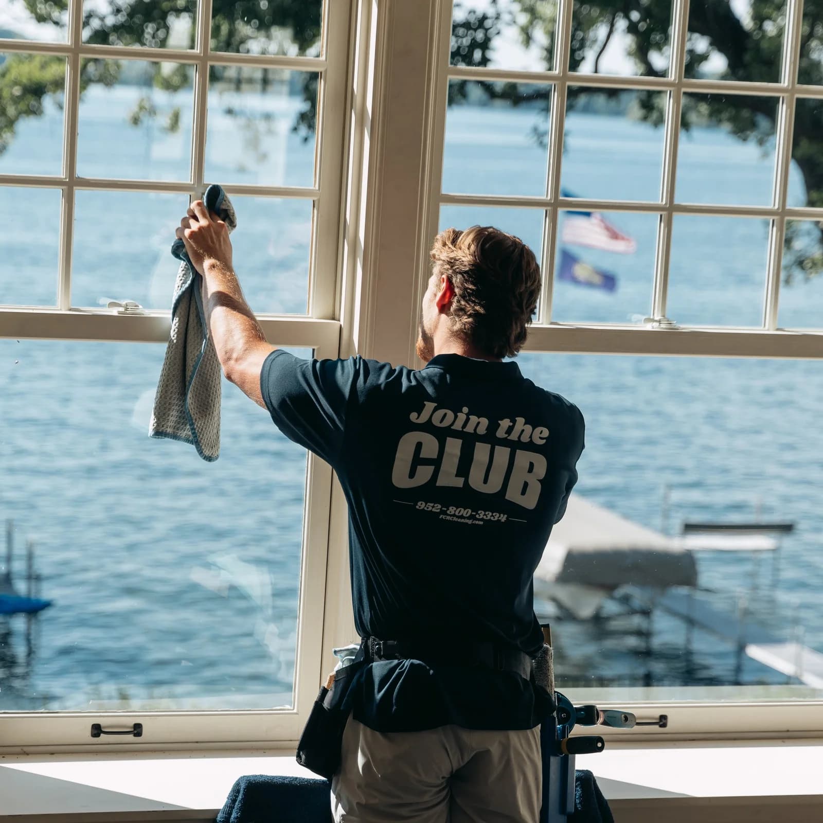 Close-up of interior window cleaning with a lake view and docked boats behind the glass