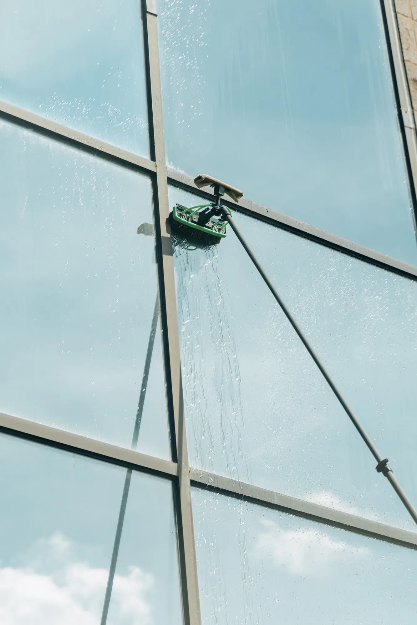Pure water brush working across sky-reflecting commercial glass