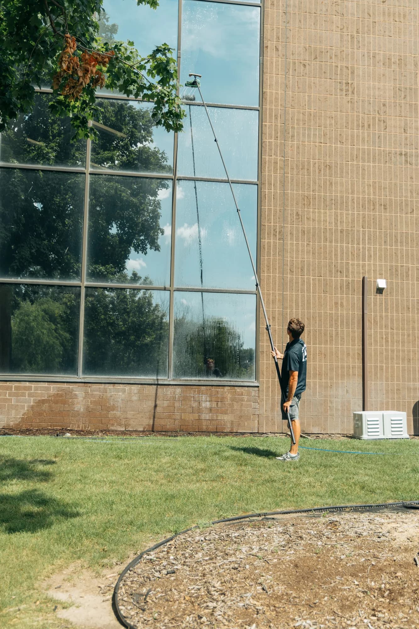 FCR technician cleaning a multi-story office building with a water-fed pole
