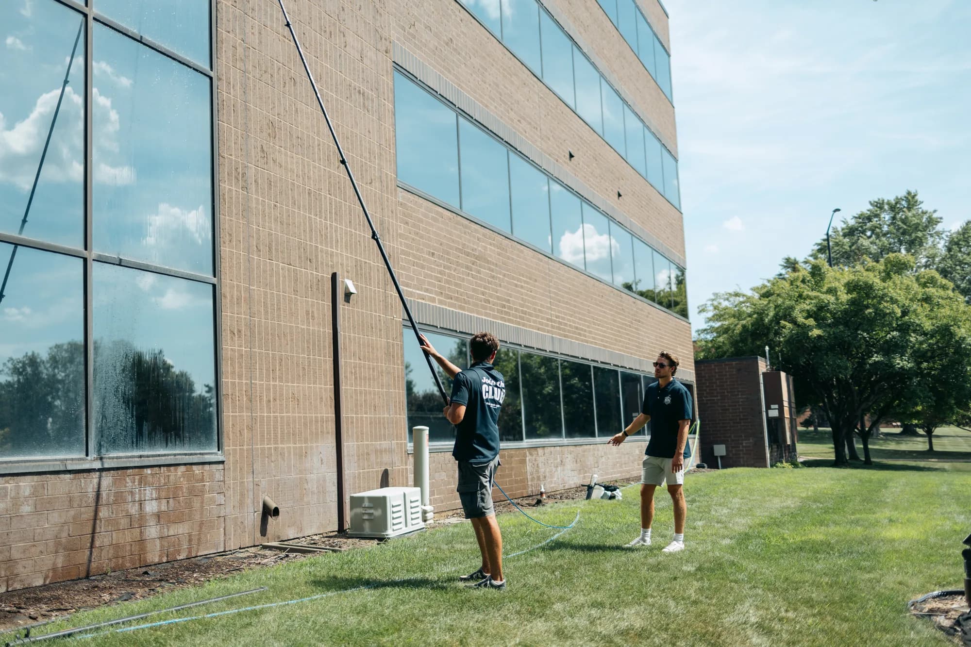 Two FCR technicians working a commercial building with water-fed poles