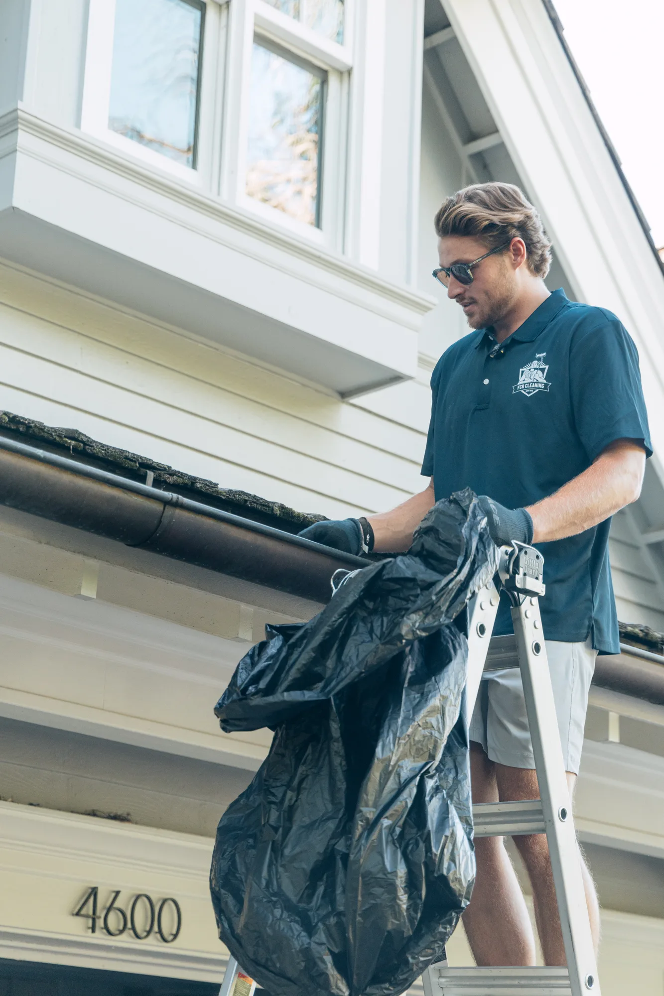 FCR Cleaning technician bagging every leaf and clump from the gutter line — full-service gutter cleaning Twin Cities MN