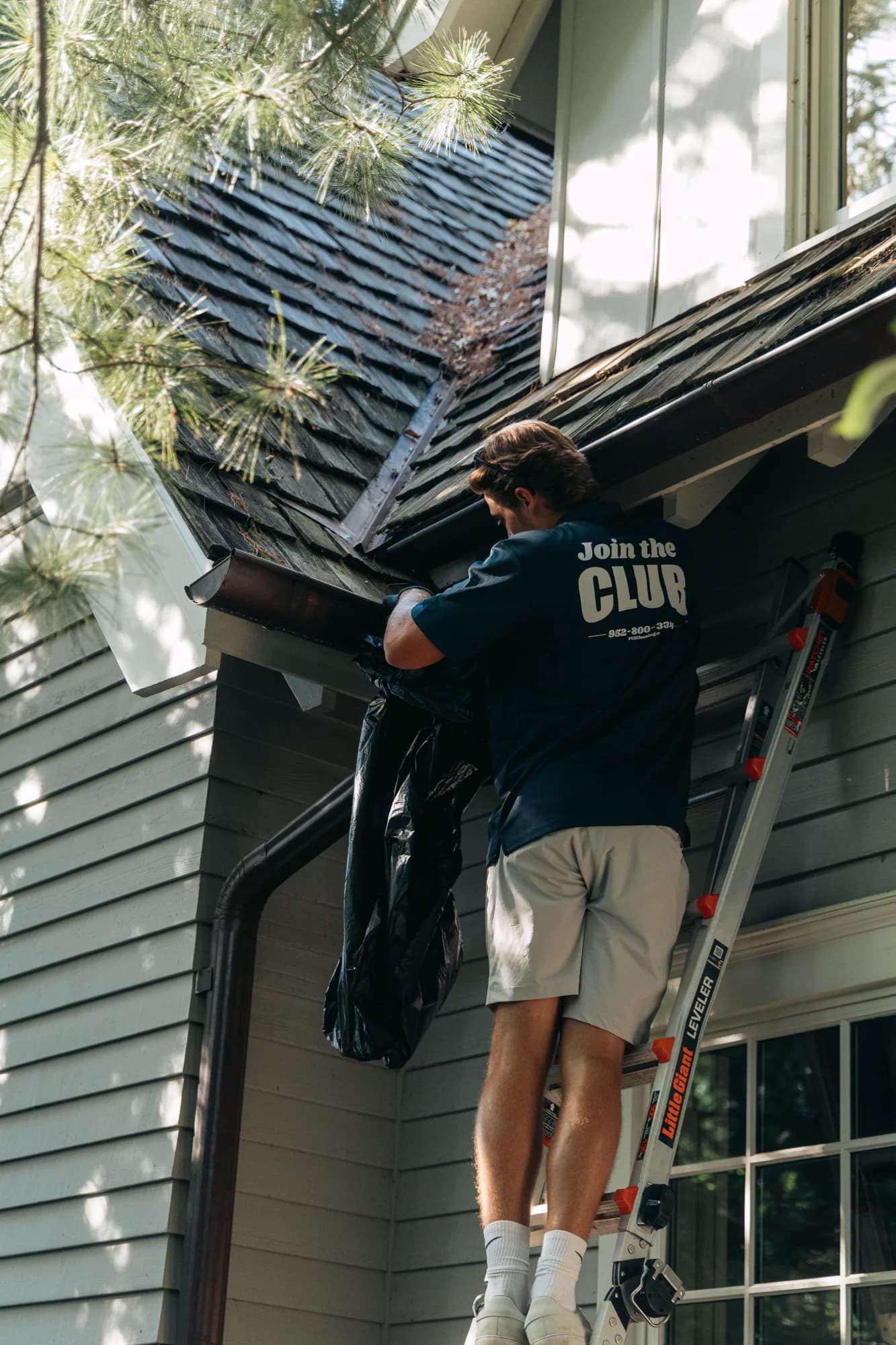 FCR technician clearing gutters on a cedar-shake roof — gutter cleaning Twin Cities MN