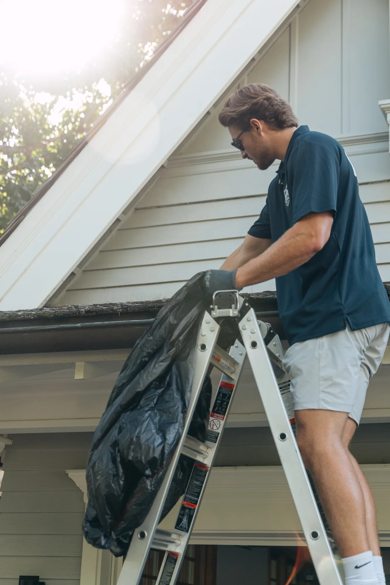 Technician clearing debris from the gutter at the roof edge