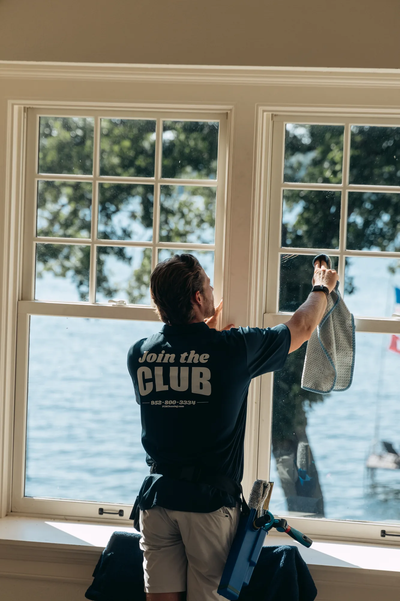 Technician wiping down a lakeside window — interior window cleaning Twin Cities MN